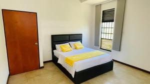 een slaapkamer met een bed met gele kussens en een deur bij Hospedaje El Caminante CAPI in Capitanejo +8 foto's