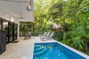 an outdoor patio with a swimming pool and trees at Four Winds Properties A Short Walk to the Beach in Nosara