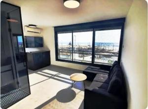 a living room with a couch and a large window at Ryo 11 דירת נופש חדשה על חוף הים נוף לים in Bat Yam