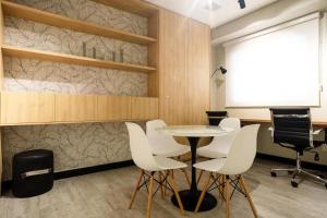 a meeting room with a table and white chairs at Studio moderno com garagem no kobrasol in São José +31 photos
