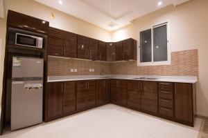 a kitchen with wooden cabinets and a refrigerator at Towlan Alfalah in Riyadh