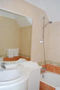 a bathroom with a sink and a tub and a mirror at Hostellerie de la Motte jean in Saint-Coulomb