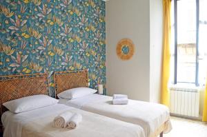 two beds in a room with a floral wallpaper at Casa Ninetta Caprarola in Caprarola