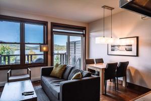 a living room with a couch and a table at Lakefront Mountain View - Resort Loft in Lac-Superieur