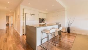 a kitchen with white cabinets and a counter and stools at 9/4 The Esplanade, Cowes - Cscape in Cowes