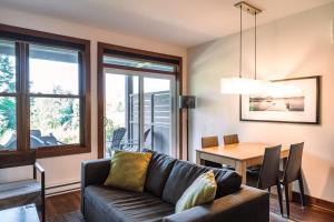 a living room with a couch and a table at Lakefront and Mountain View - Resort Loft in Lac-Superieur