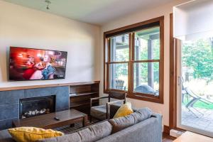 a living room with a couch and a fireplace at Lakefront and Mountain View - Resort Loft in Lac-Superieur