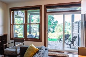 a living room with a couch and a sliding glass door at Lakefront and Mountain View - Resort Loft in Lac-Superieur