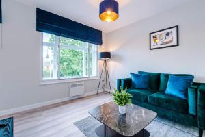 a living room with a green couch and a glass table at Elysée Suites - Spacious 1 Bed Flat in Southport in Southport