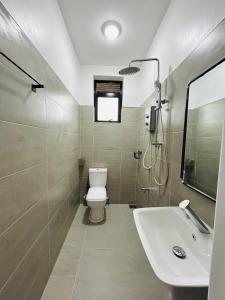 a bathroom with a toilet and a sink at BeHomu Apartments Kampala in Kira