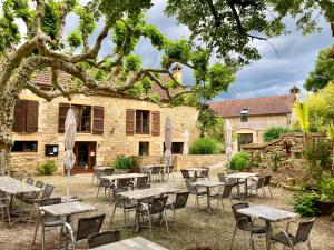 a group of tables and chairs in front of a building at La Ferme de Maraval in Cénac-et-Saint-Julien