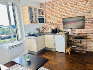a kitchen with a white refrigerator and a brick wall at Le Cocon au bord de la mer in Trouville-sur-Mer