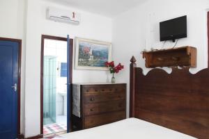 a bedroom with a bed and a dresser with a television at Pousada Santa Rita in Paraty