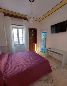 a bedroom with a purple bed and a flat screen tv at Palazzo Sardanelli in Pizzo