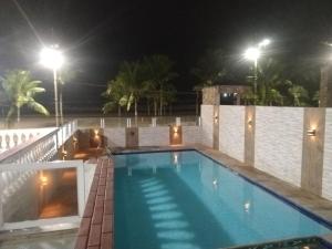 a swimming pool at night with lights on a wall at Apto Frente ao Mar - Vila Tupy in Samaritá