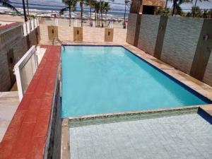a swimming pool with blue water and a beach at Apto Frente ao Mar - Vila Tupy in Samaritá