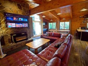 a living room with a leather couch and a fireplace at Renovated 6 Bedroom Chalet Hot Tub Near Village in Blue Mountains