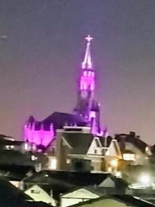 Un edificio iluminado con una torre con luces moradas. en Apartamento a 3min do centro Canela, en Canela