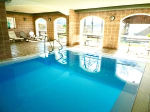 a swimming pool with blue water in a building at Ferienwohnung Ferienanlage Pool Sauna Hallenbad Nähe Skipiste Bayer Wald in Hauzenberg