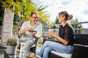a man and a woman sitting in chairs eating food at Pension Linder in Seeboden