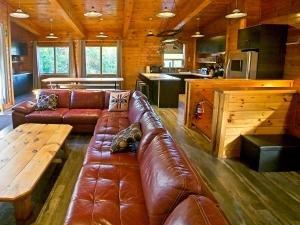 a living room with a brown leather couch and a table at Renovated 6 Bedroom Chalet Hot Tub Near Village in Blue Mountains