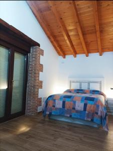 a bedroom with a bed and a brick wall at Casa vacacional Los Enserados in Renedo de Piélagos