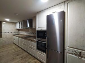 a kitchen with a stainless steel refrigerator and white cabinets at Casa vacacional Los Enserados in Renedo de Piélagos
