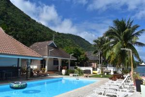 a resort with a swimming pool and lounge chairs at Pension de famille HITI MOANA VILLA in Papara