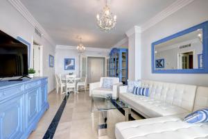 a living room with blue and white furniture and a chandelier at Banana Beach primera línea de playa in Marbella