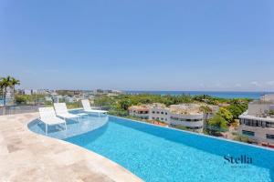 una piscina con 2 sillas y el océano en Chic Studio at My Menesse In Playa with Roof Pool, en Playa del Carmen