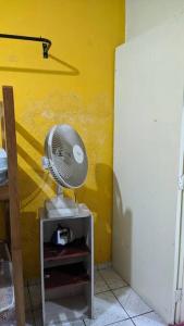 a fan sitting on top of a cabinet next to a yellow wall at Casa alojamento em Jandira in Jandira
