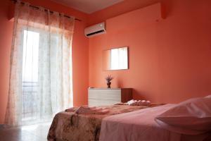 a bedroom with orange walls and a bed and a window at Mati Rooms in Giarre