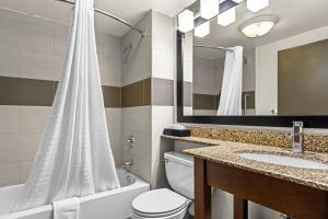 a bathroom with a toilet and a sink and a mirror at Spark by Hilton Syracuse Carrier Circle in East Syracuse