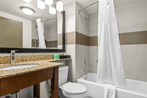 a bathroom with a sink toilet and a mirror at Spark by Hilton Syracuse Carrier Circle in East Syracuse +2 photos