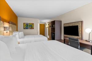 a hotel room with two beds and a desk and a tv at Spark by Hilton Syracuse Carrier Circle in East Syracuse