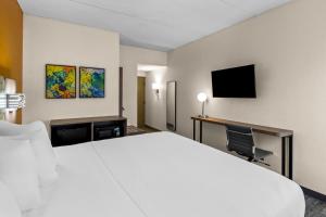 a hotel room with a large bed and a desk at Spark by Hilton Syracuse Carrier Circle in East Syracuse