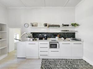 a kitchen with white cabinets and a black and white rug at Classy and Newly Renovated Studio in Observatory in Cape Town