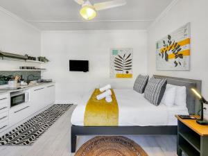 a bedroom with a large bed and a kitchen at Classy and Newly Renovated Studio in Observatory in Cape Town