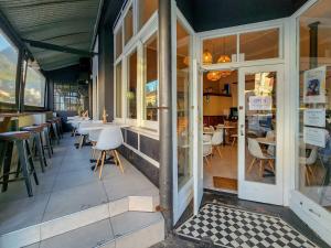 a restaurant with white chairs and tables and windows at Classy and Newly Renovated Studio in Observatory in Cape Town