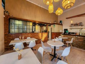 a restaurant with white tables and white chairs at Classy and Newly Renovated Studio in Observatory in Cape Town