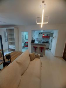 a living room with a large couch and a kitchen at Apartamento Estúdio em Caraguatatuba com Garagem in Caraguatatuba