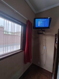 ein Fernseher in einem Zimmer mit Fenster und einem Fernseher in der Unterkunft Apto no Centro de Bertioga, próx a Praia da Enseada e da Balsa com acesso a Prainha Branca, Acomoda até 6 pessoas in Bertioga
