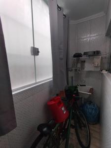 ein Fahrrad, das in einem Badezimmer neben einem Fenster geparkt ist in der Unterkunft Apto no Centro de Bertioga, próx a Praia da Enseada e da Balsa com acesso a Prainha Branca, Acomoda até 6 pessoas in Bertioga + 11 Fotos