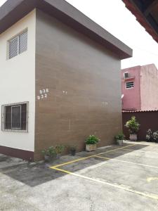 ein Gebäude mit einer rosa Tür und einem Parkplatz in der Unterkunft Apto no Centro de Bertioga, próx a Praia da Enseada e da Balsa com acesso a Prainha Branca, Acomoda até 6 pessoas in Bertioga