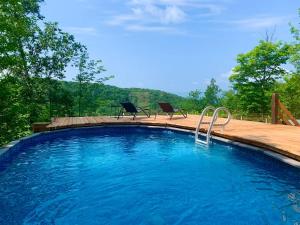 a swimming pool with two chairs sitting on a wooden deck at Blue Hill Pool spa game room mountain view in Morin Heights