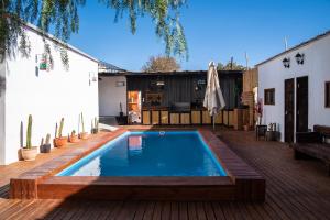 a swimming pool in a backyard with a wooden deck at Puna Hostel in San Pedro de Atacama