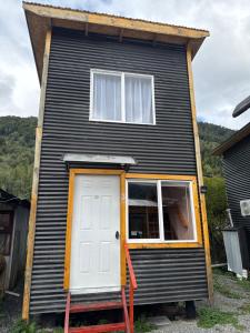 a black house with a white door and windows at Cabañas mateo 03 nuevo in Puerto Puyuhuapi +2 photos