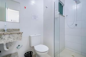 um banheiro branco com vaso sanitário e chuveiro em Residencial Flórida I em Bombinhas mais 18 fotografias