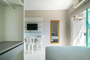 a bedroom with a bed and a table and a television at Residencial Flórida I in Bombinhas