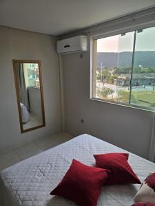 um quarto com uma cama com almofadas vermelhas e um espelho em Residencial Flórida I em Bombinhas